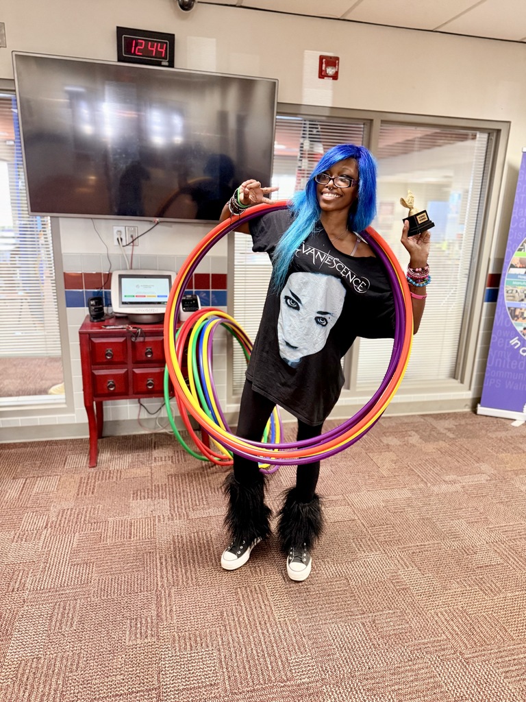 A student holding a trophy with hula hoops around her shoulders