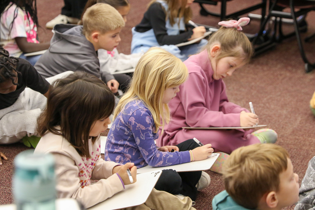 three girls writing on a dry erase board