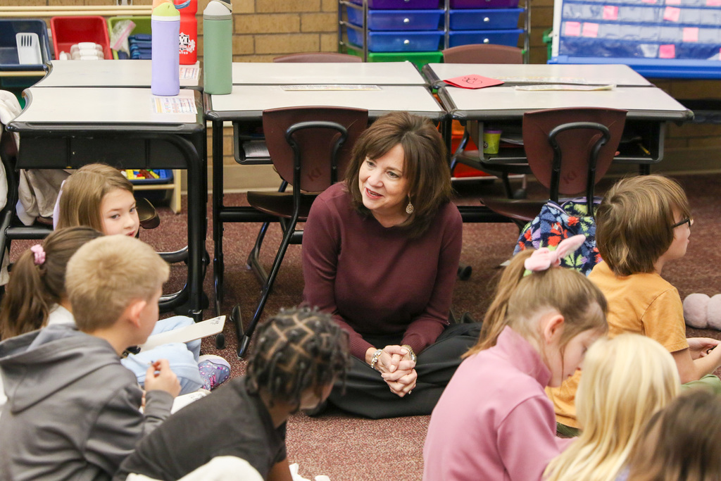 Dr. Butterfield sitting on the ground with students