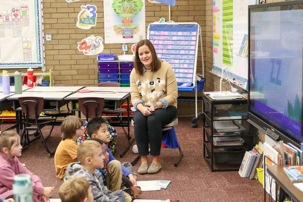 teacher smiling at students sounding out letters