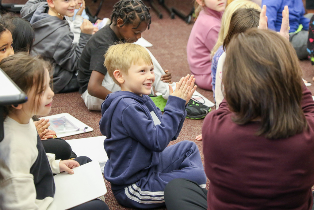 boy smiling and clapping and looking at dr. butterfield