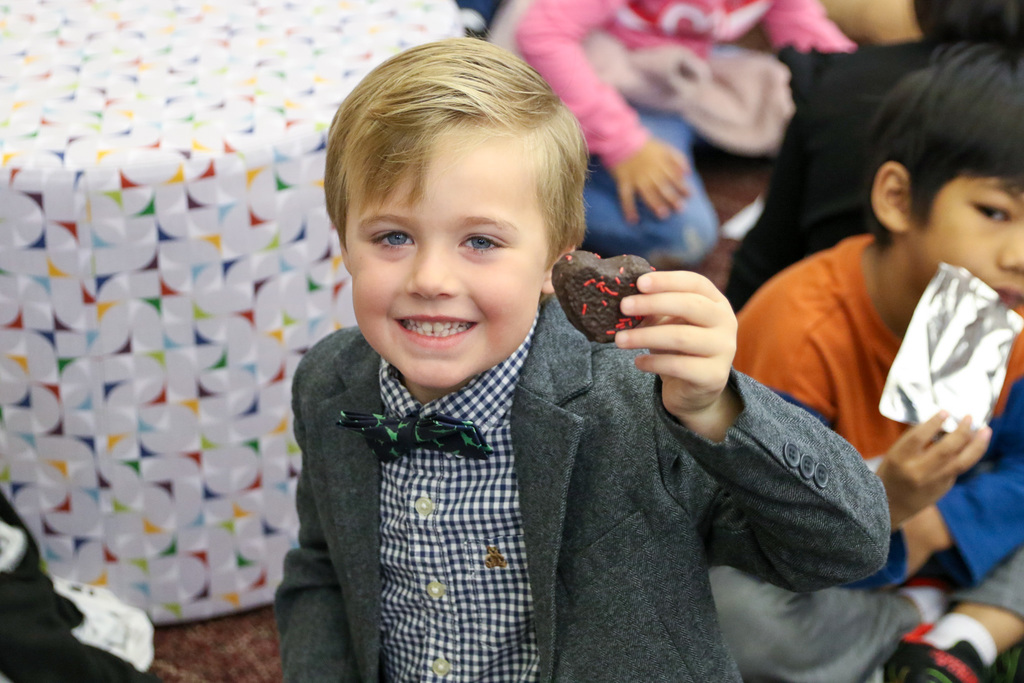 boy holding up a wedding cake piece of a heart