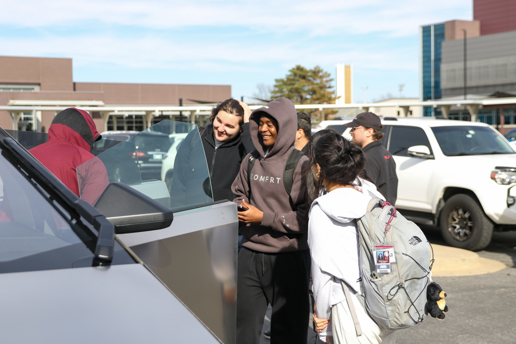 students stand outside the tesla smiling
