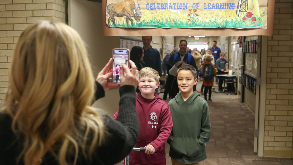 two boys pose infront of a banner that says oklahoma adventure celebration of learning