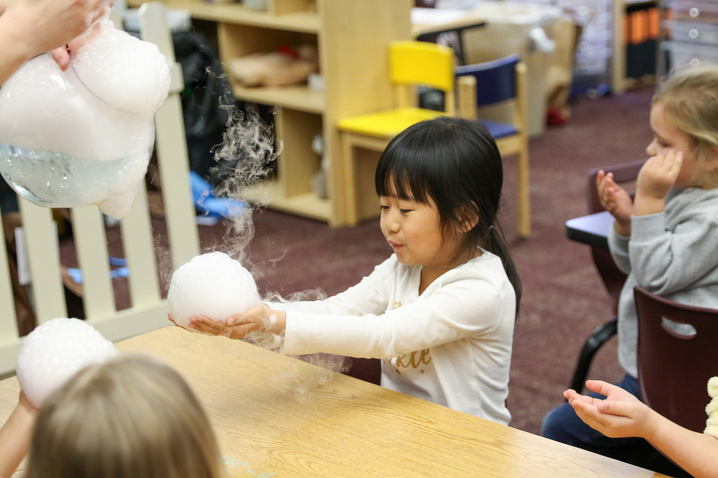 girl playing with bubbles on table