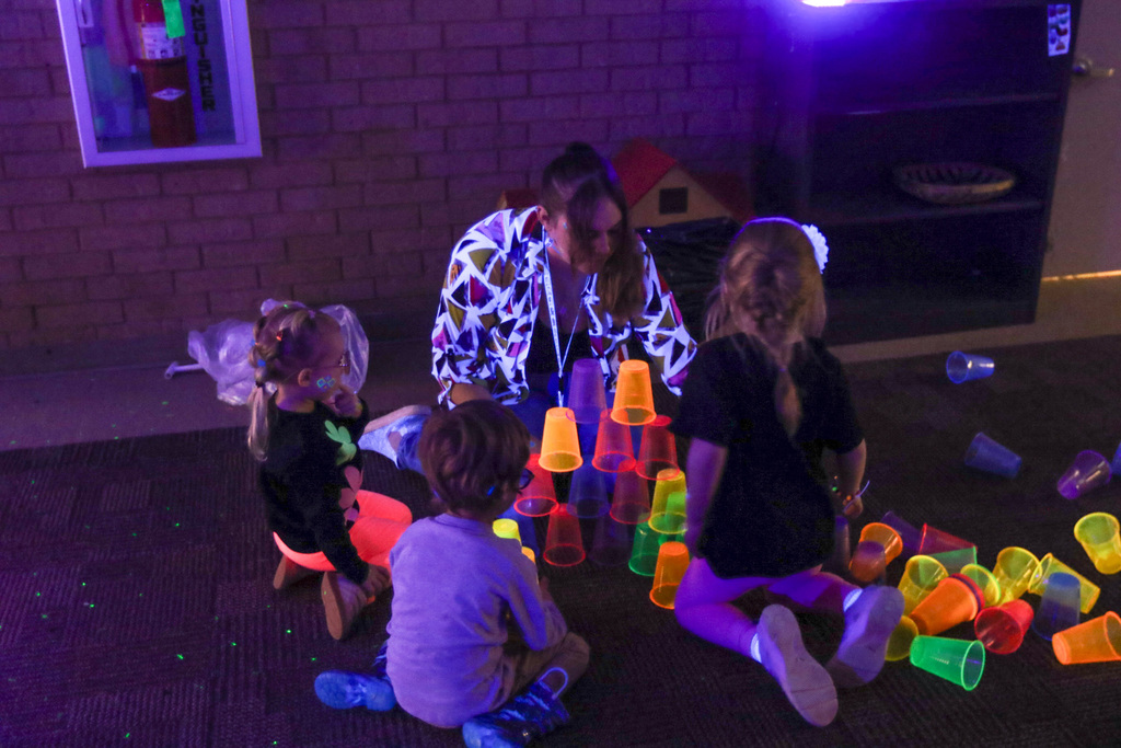 teacher stacking glow in the dark cups with students