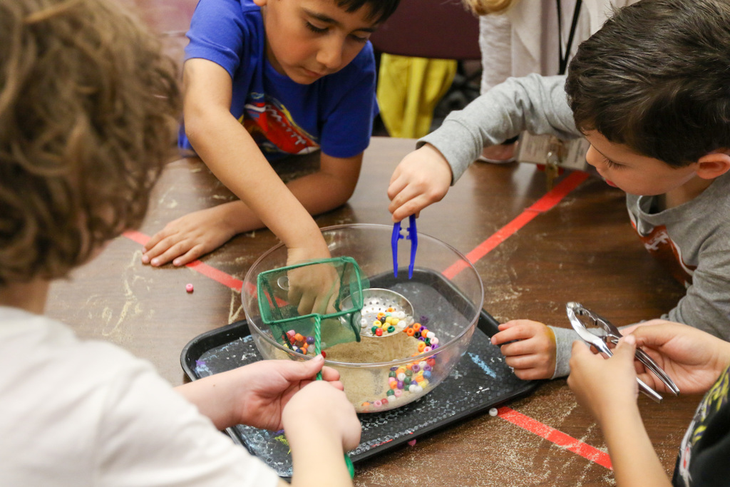 students using tools to get beads out of a bowl