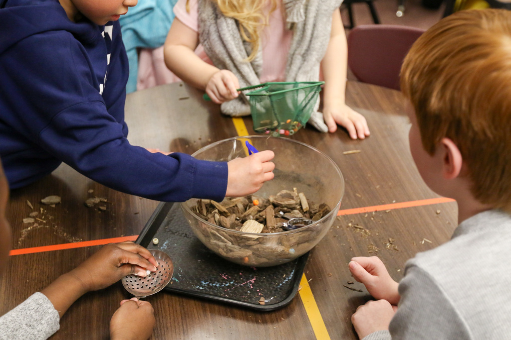 students using tools to extract beads from a bowl