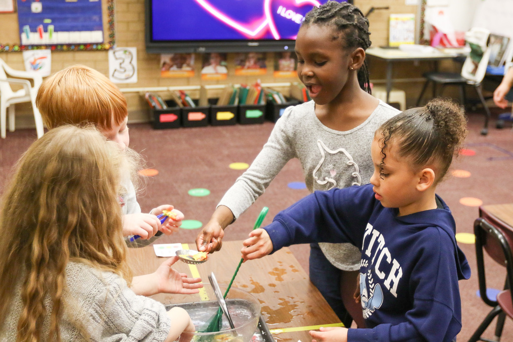 students getting plastic fish out of a bowl with tool. stuednt smiling at the fish she caught