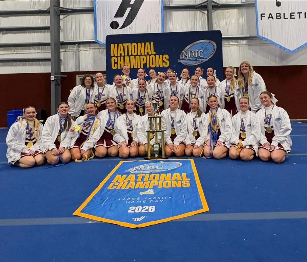 Jenks Varsity Pom team posing for a pic with their first place trophy and banner for gameday performance