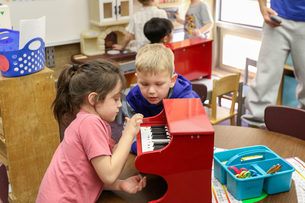 girl and boy playing a piano