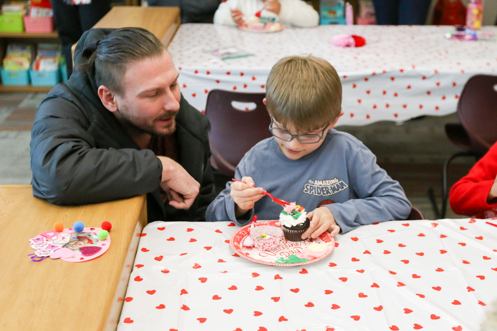 father and son decorating a cupcake