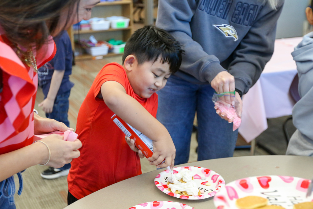 boy putting whipped cream on his pancakes