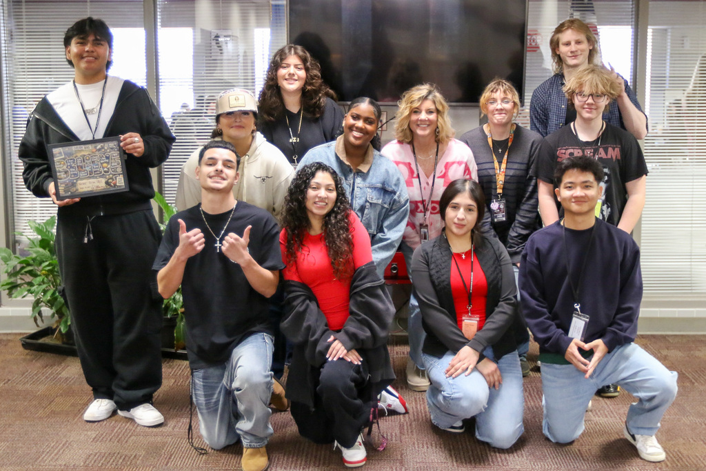 Jenks Alternative Center Principal Amie Hardy surrounded by 11 smiling students who are the most recent trimester graduates from the Alternative Center