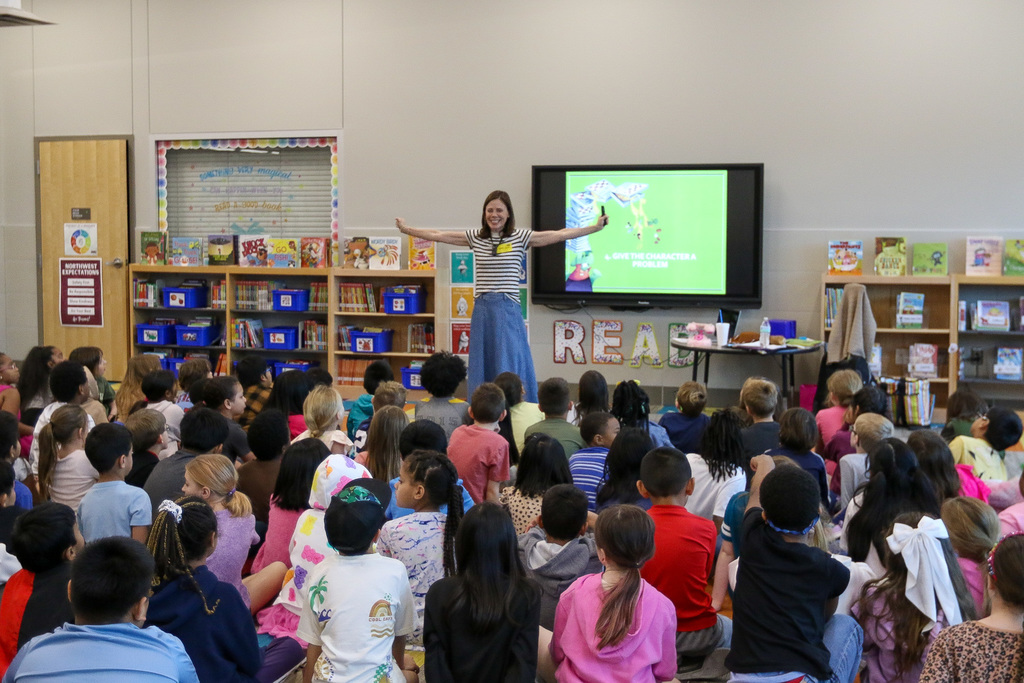 tammi with her arms up presenting to students
