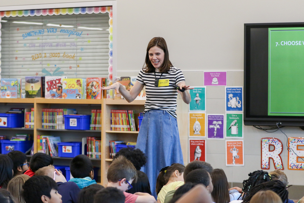tammi with her arms up presenting to students