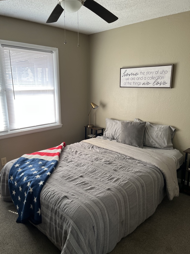 photo of empty bedroom with American flag blanket draped over the bed