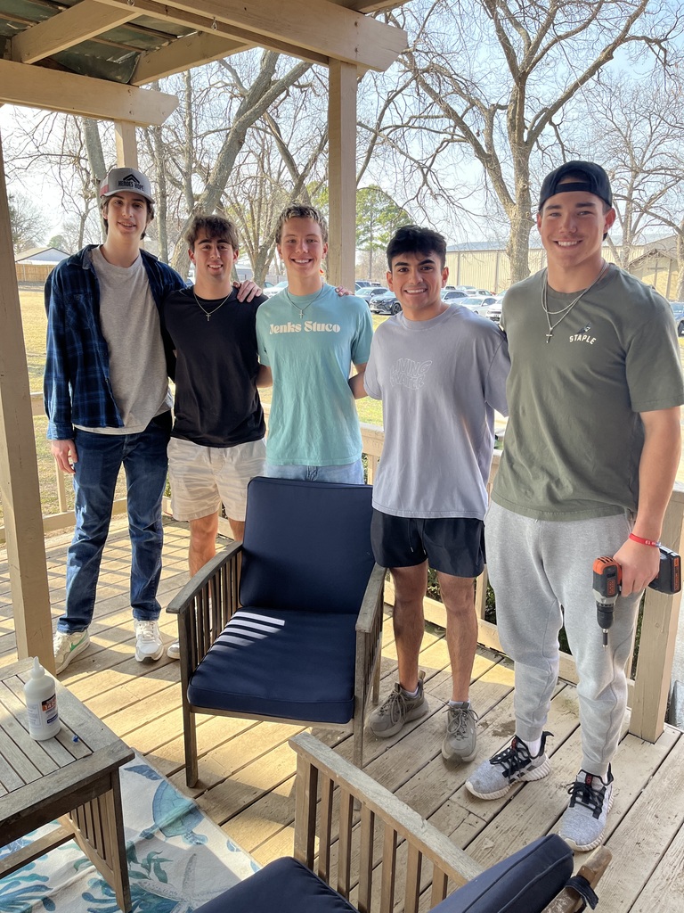 Five teenage boys posing for group pic after assembling outdoor patio chairs on back deck of home for veterans