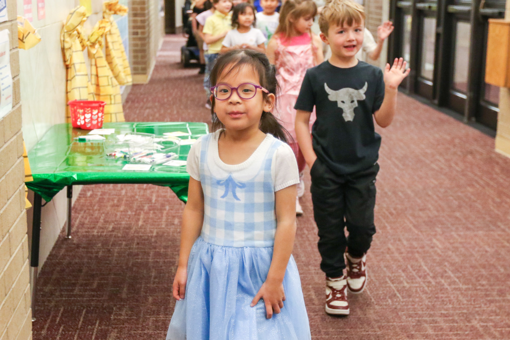 little girl walking in the parade dressed as dorthy