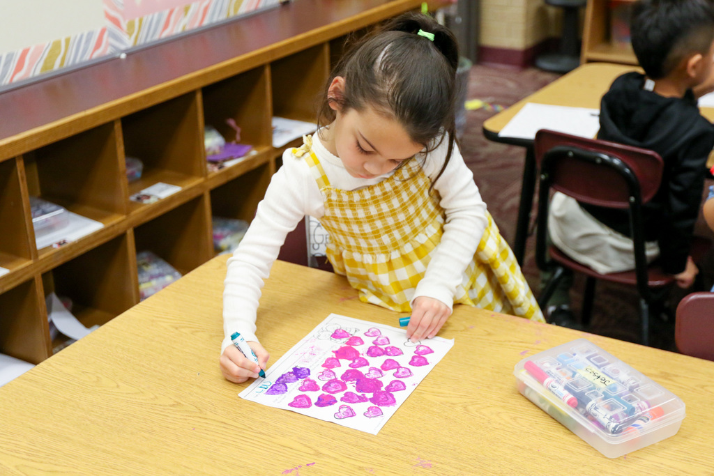 student is signing her name on her drawing of hearts