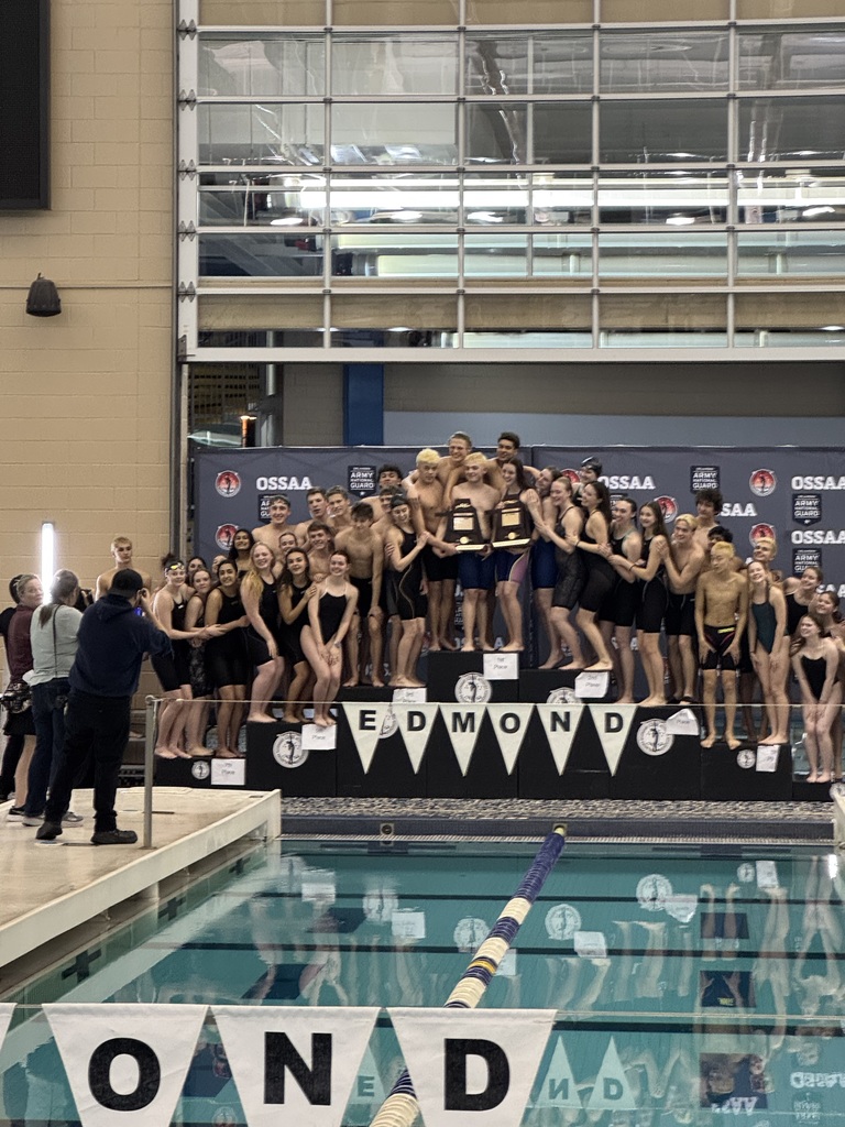 photo of Jenks boys and girls teams gathering together on a podium holding state championship trophies