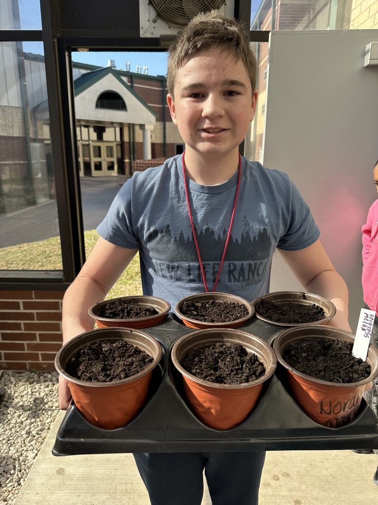 student holding 6 pots of dirt