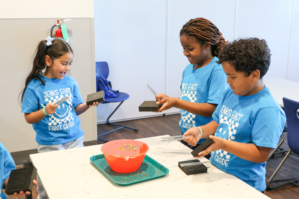 Students tap a bowl with rice on top with a tuning fork that vibrates the plastic wrap to make the rice dance!