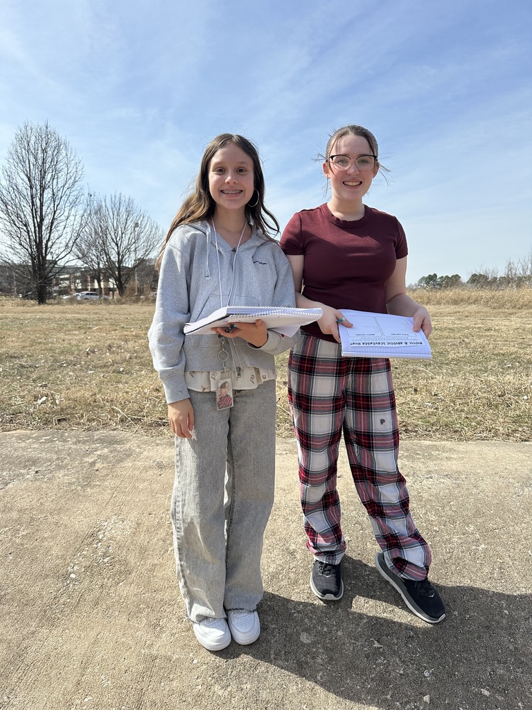 2 girls standing with school work