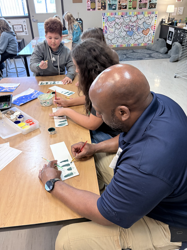Student and family during Specials with Someone Special (in art- painting trees).