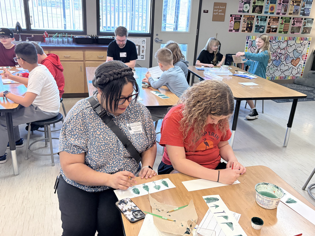 Student and family during Specials with Someone Special (in art- painting trees).