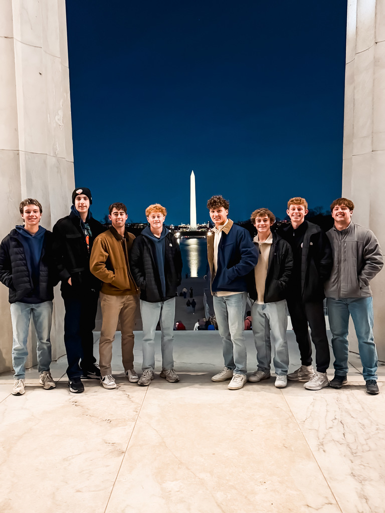 Group of eight male students in Washington D.C. with Washington Monument in background at night