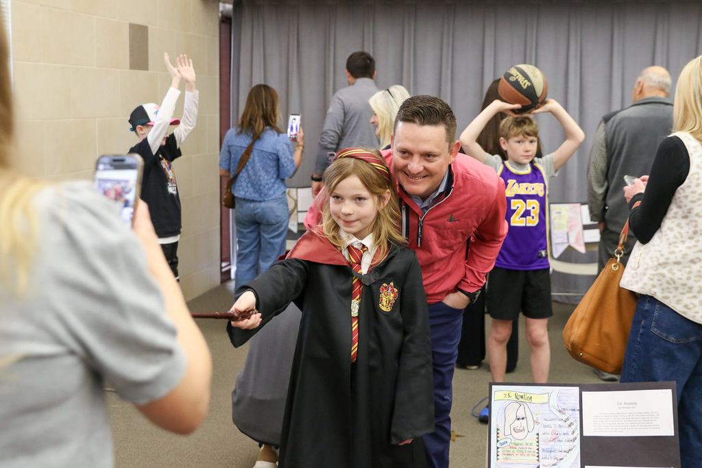 Student dressed up as a character from a JK Rowling book posing with her family for a photo.