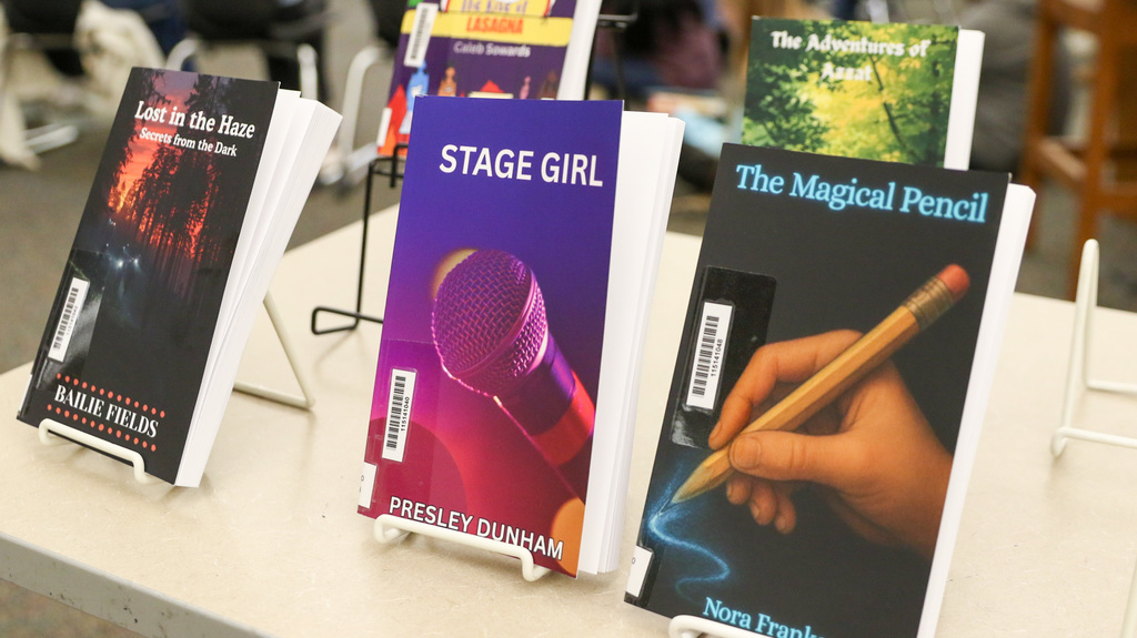 Photo of some of the students books up close. 3 books in focus are Lost in the Haze, Stage Girl, and the Magical Pencil.