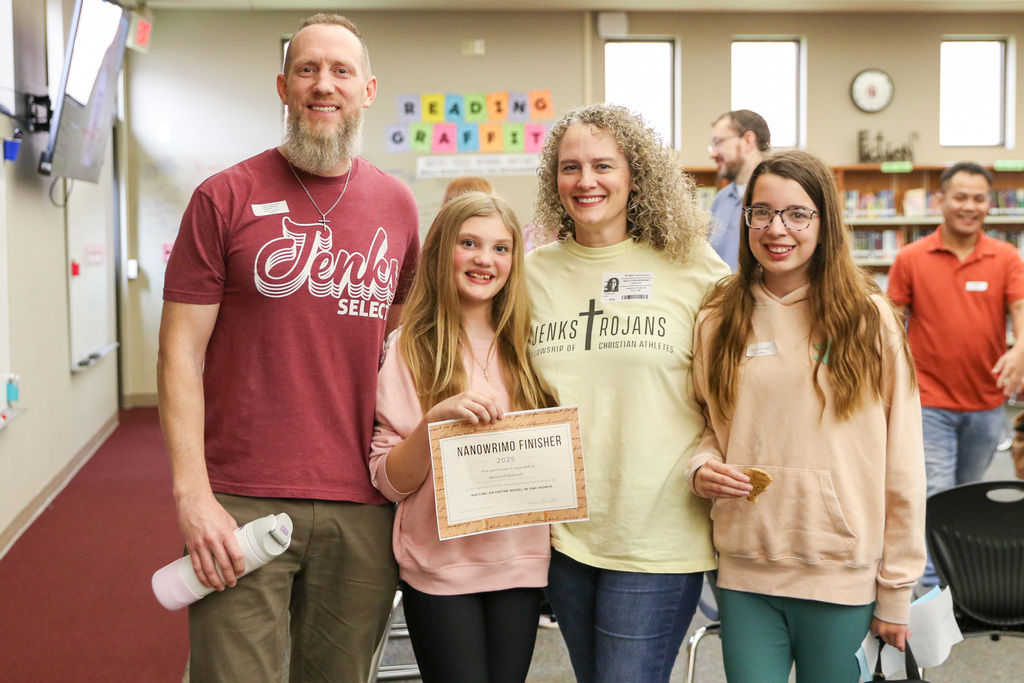 A girl with her family standing with her NaNoWriMo finisher certificate posing for a photo.