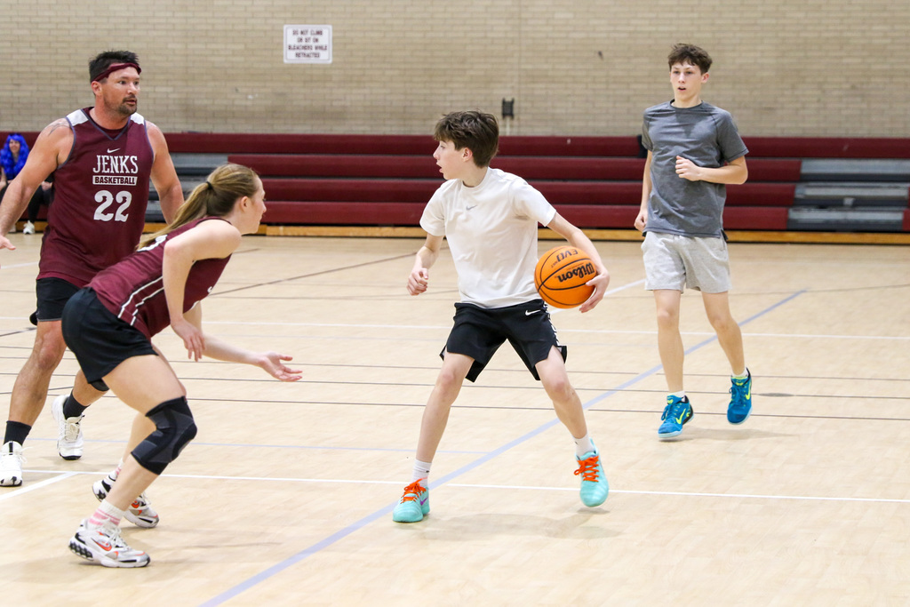 Student dribbling the ball while being guarded by two teachers.