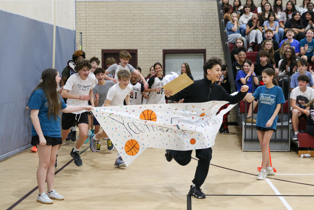 Students running through a banner from the locker room.