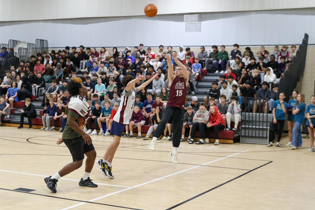 Teacher shooting the ball with students trying to block his shot.