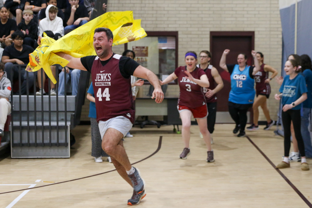 Teachers running out the locker room. Teacher in front has the banner they ran through around his arm.
