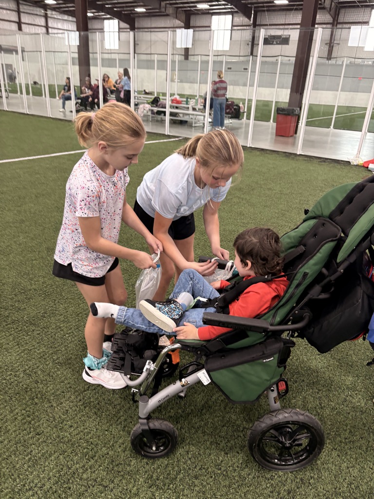 Two girls helping a student in a wheelchair.