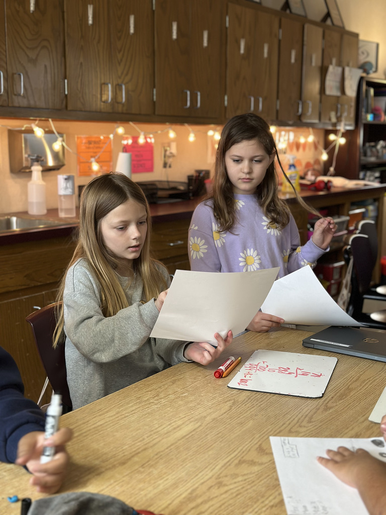 Two students working together to analyze data from a basketball game to work on math skills.