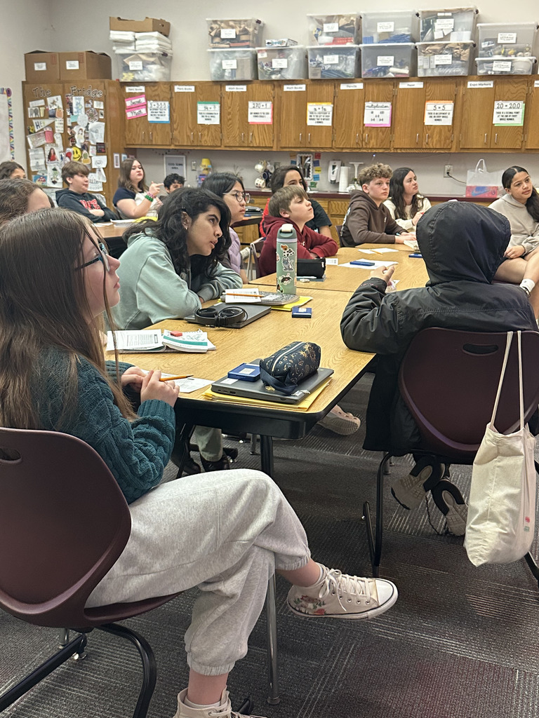 A class watching a clip from a basketball game in order to analyze data to work on math skills.