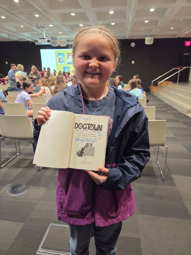 Picture of a JWI student at the Tulsa Central Library, student holding signed copy of Dog Town.