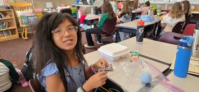 student doing crochet at the lunch club