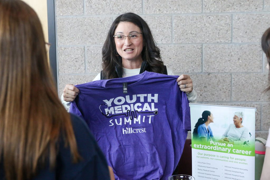 hilcrest employee holding a purple shirt that says youth medical summit