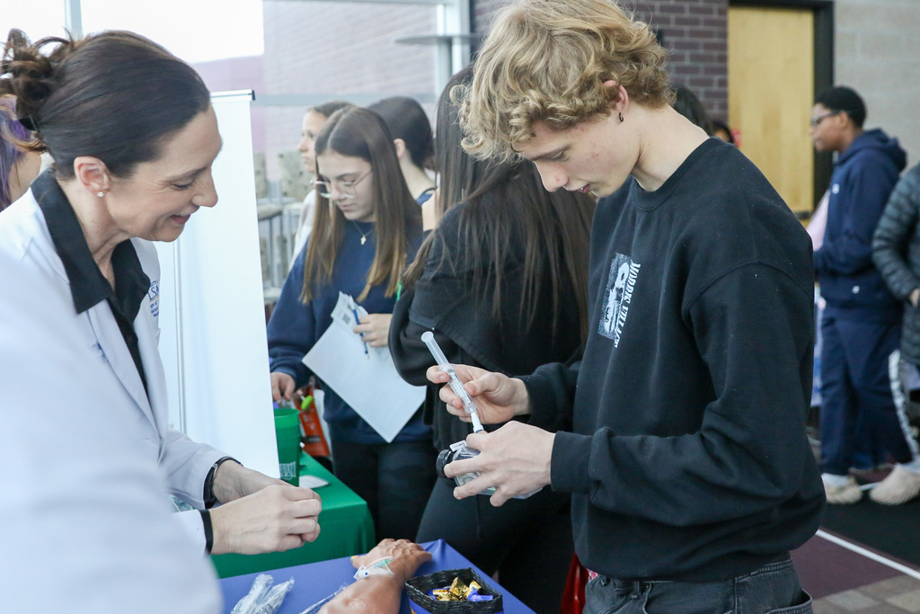 student uses a prop medical device with the help of a doctor.