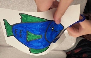 cutting out a blue and green paper fish