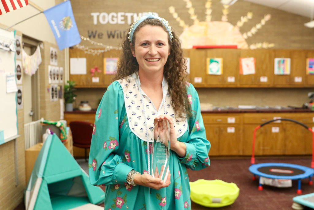 Teacher of the Year Macy Worley in her classroom holding her award smiling for a photo