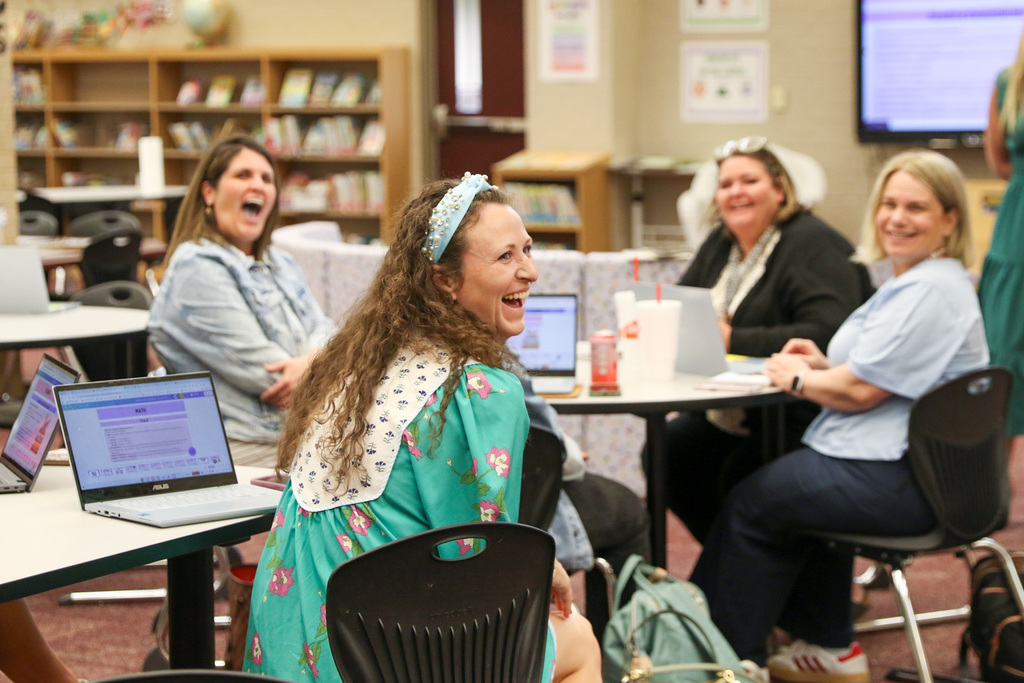 Macy looking to the right smiling and laughing at Dr. Butterfield who is not pictured as she announces to other teachers in the room that Macy is the district teacher of the year.