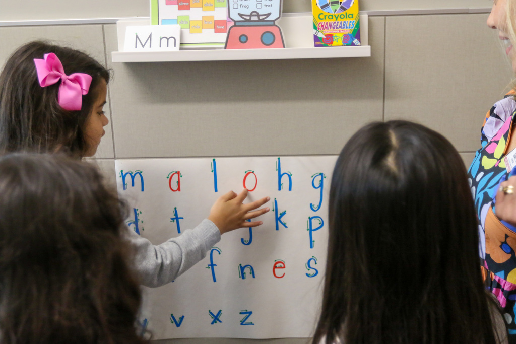 student using her finger to learn how to write letters correctly. she is outlining an O in this photo.
