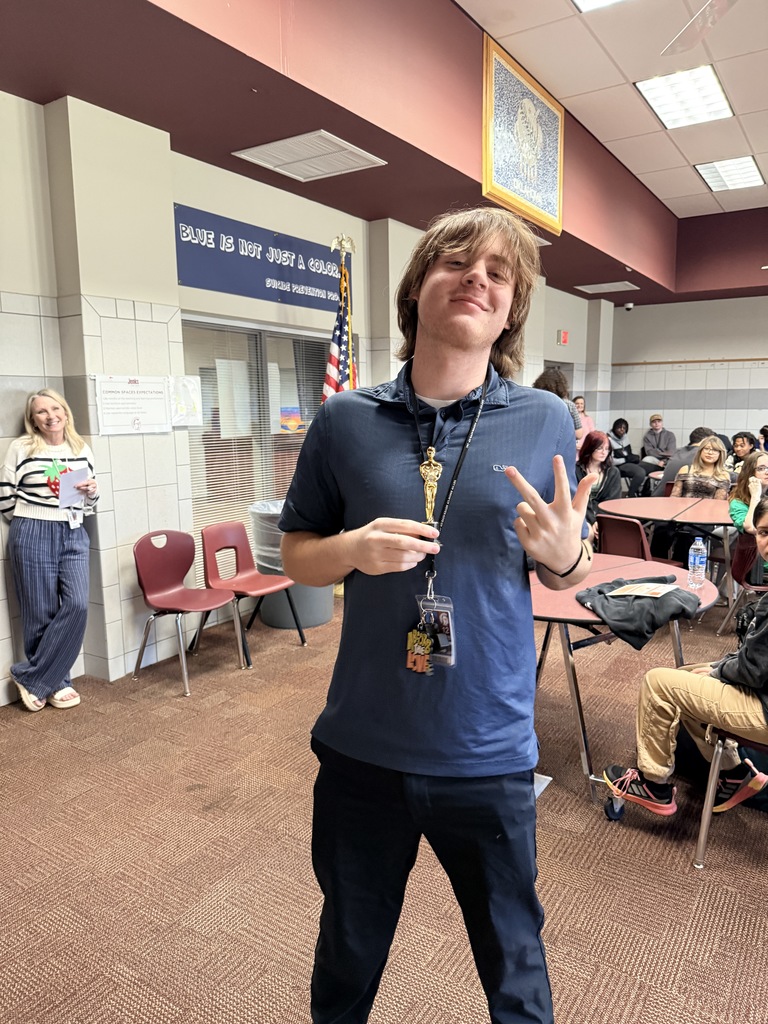 a student holding a replica of an Oscar award